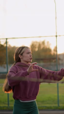 el entrenador salta y golpea la pelota de voleibol, interactuando con alguien en el fondo, la luz del sol dorada brilla a través del campo abierto y la cancha de voleobol durante la sesión de entrenamiento