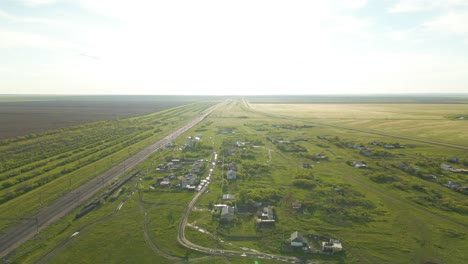 Road-Between-Vast-And-Green-Fields-With-Houses---Aerial-Drone-Shot