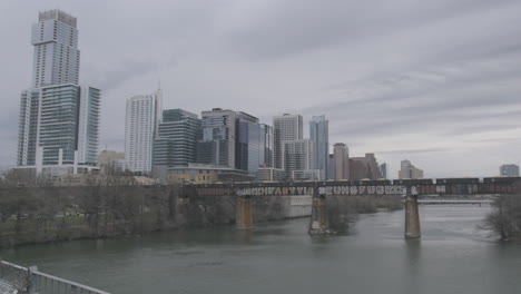 a freight train crosses the colorardo river and heads into downtown austin