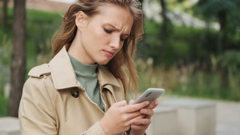 caucasian female student using smartphone outdoors.