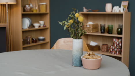 a round table with a vase of yellow flowers and a bowl of cookies in a modern interior.