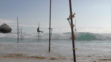 low angle, slow motion slide of sri lankan stilt fisherman moving feet out of the way of oncoming waves