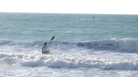 canoeist tries to get over huge waves on a beach in dubai