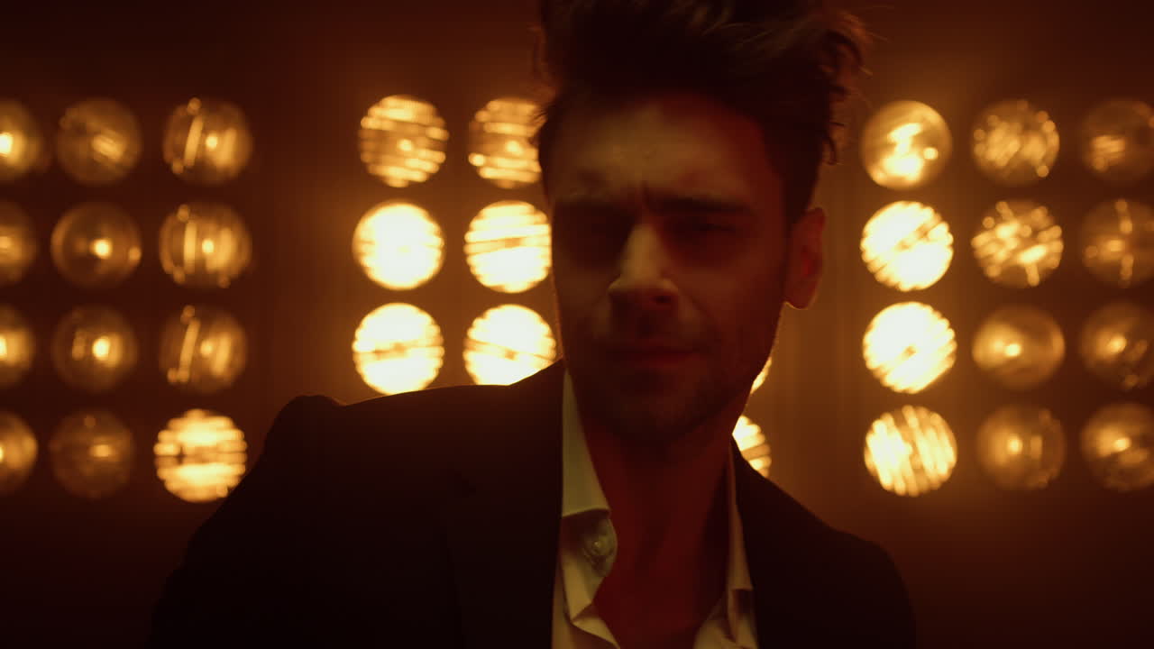 un hombre macho posando seductoramente con un traje elegante en las luces de un club nocturno de cerca.