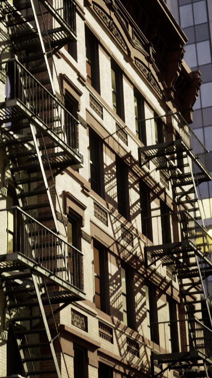 Fire escapes on a building in a busy urban area during daylight hours