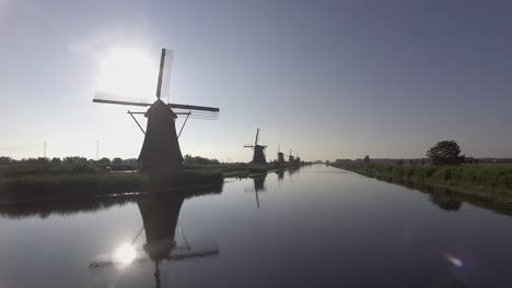 a drone shot panning left, around dutch windmills during sunrise