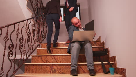 Typing-on-laptop-speaking-on-phone-sitting-on-stairs