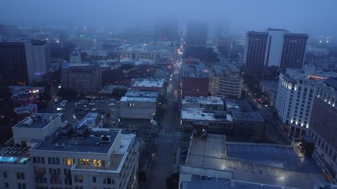 A drone flies alongside a flock of birds, soaring over the city as skyscrapers and bustling streets unfold below.