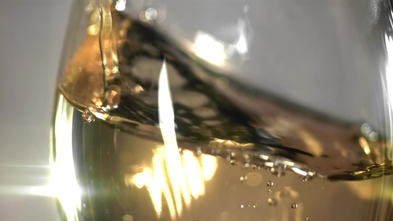 Liquido dorato scintillante che vortica in un bicchiere trasparente