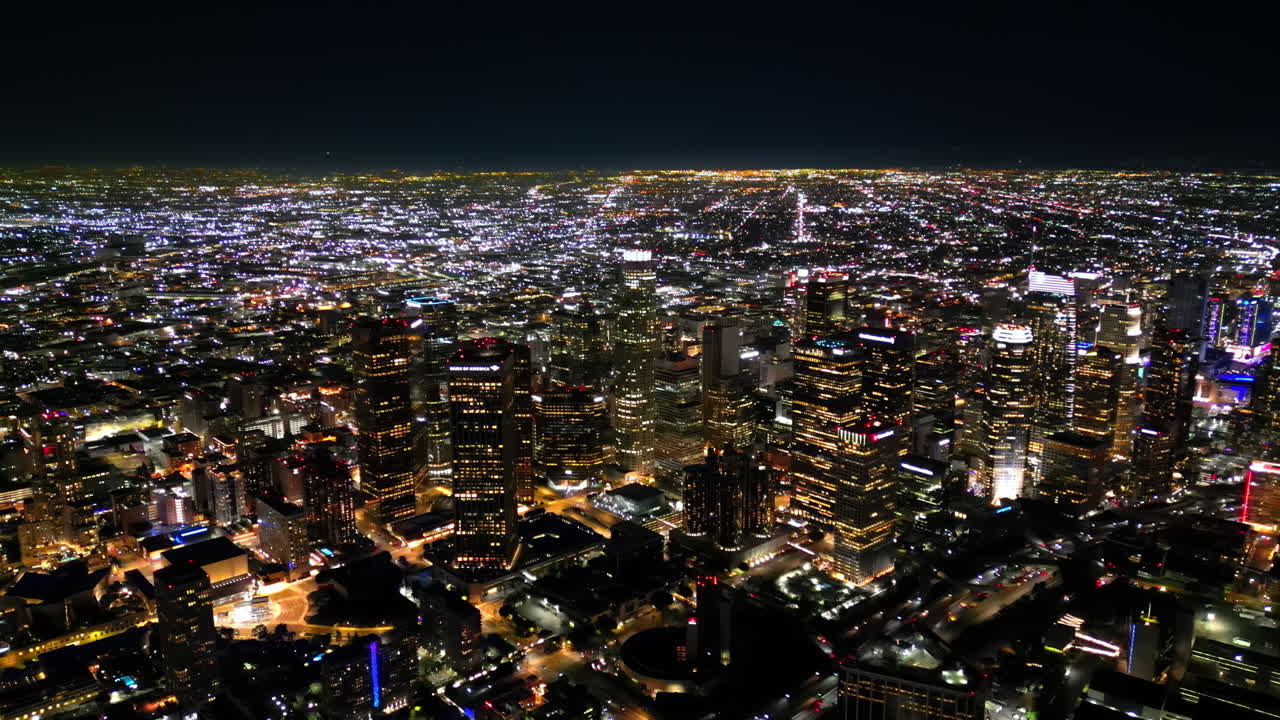Aerial drone view of Los Angeles at night, featuring endless city lights stretching to the horizon