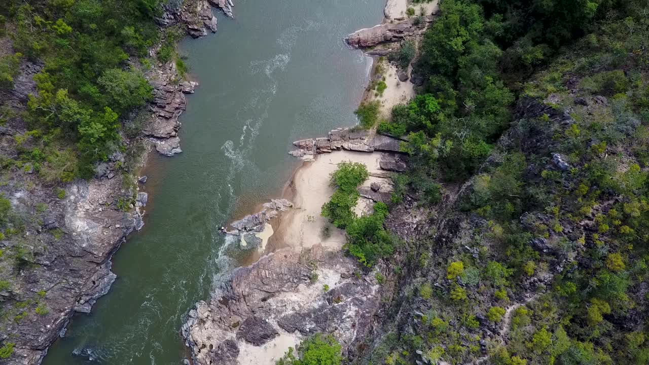 Aerial shot of a rocky and sandy riverbank in a tropical forest