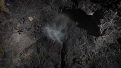 drone top down rises above blowhole in kiama nsw australia as ocean spray mist flies up and out dissipating into the air