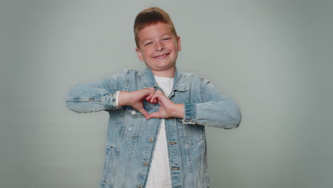 niño pequeño sonriente hace un gesto de corazón demuestra un signo de amor expresa buenos sentimientos y simpatía