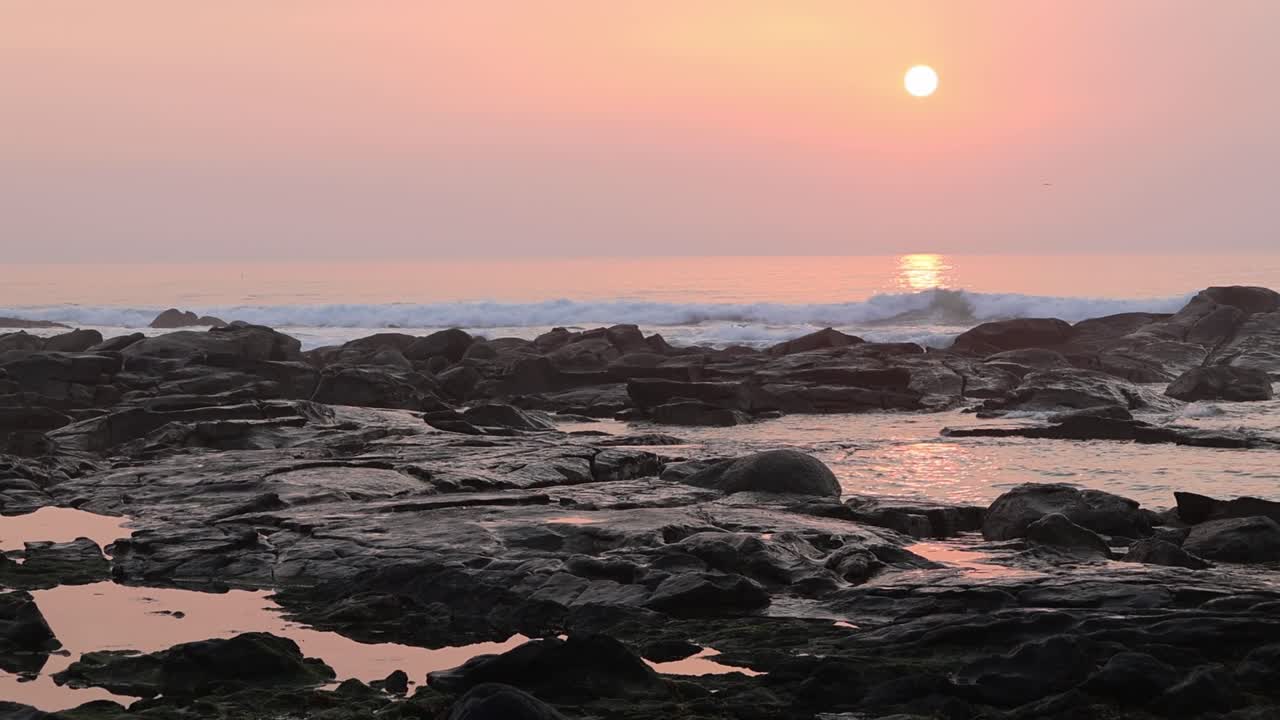Colorful sunset wit yellow, red and orange over ocean waves and rocky in nortern Portugal.