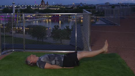 cool guy is doing flutter kicks in the evening on a modern terrace with danube river backdrop in vienna, 4k, timelapse