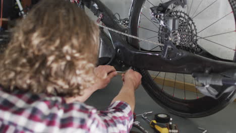 Focused-caucasian-man-repairing-bike-using-tools-in-garage