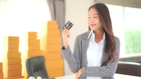 beautiful young asian business woman posing in front of camera with banks credit card, slow motion