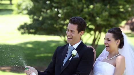 Happy-newlyweds-spraying-bottle-of-champagne