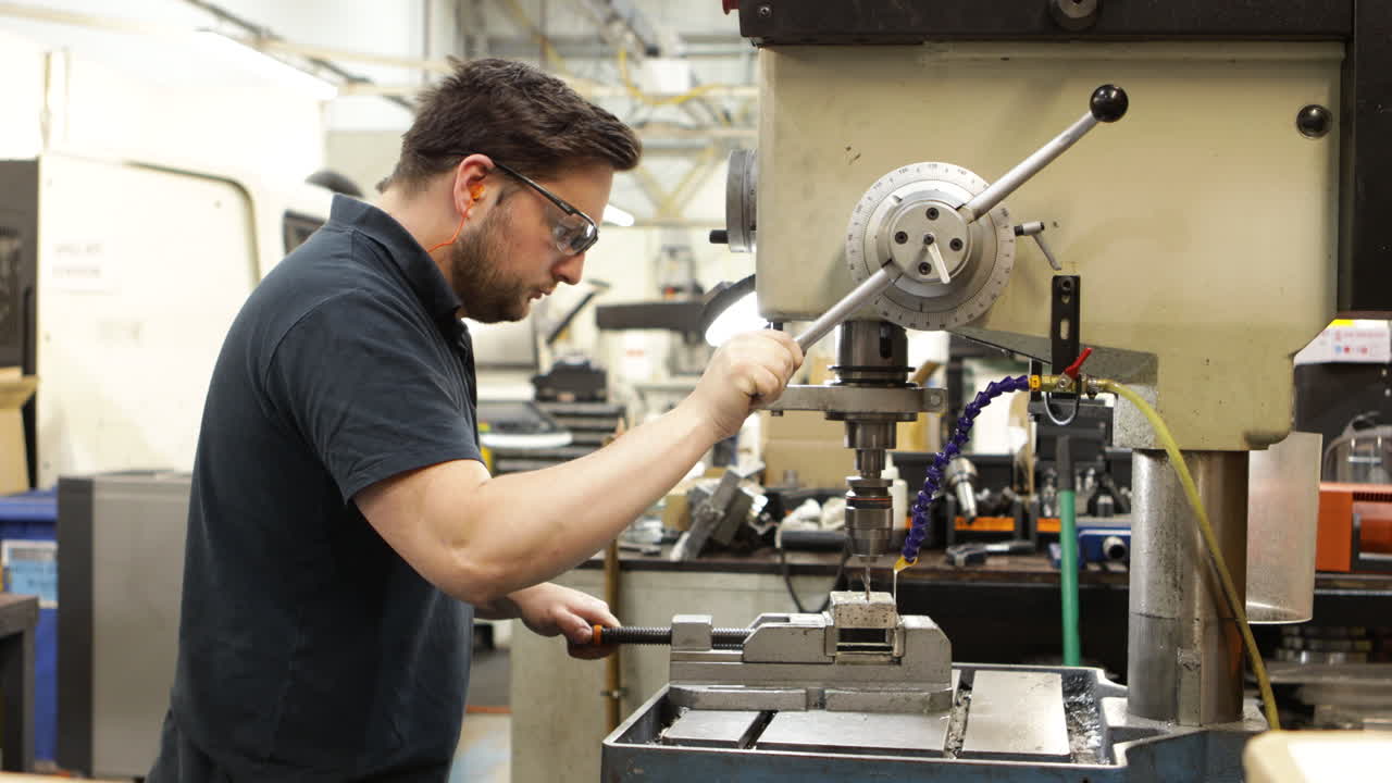 산업 환경에서 기둥 드릴을 작동하는 사람, 공예에 초점을 맞추십시오.