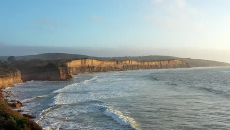 AERIAL-LIFT-Powerful-Waves-Roll-Into-Limestone-Cliffs-During-Golden-Hour