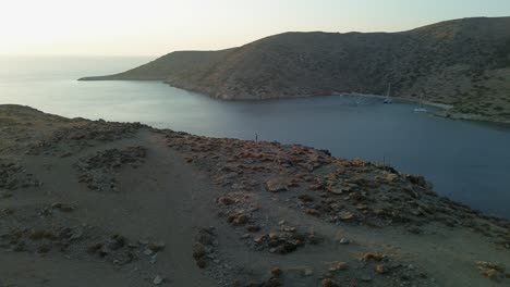 lone drone pilot standing on island ridge near sun lit ocean