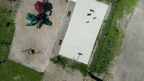 Kids-play-basketball-near-playground-and-mini-putt-summer-camp,-overhead-aerial
