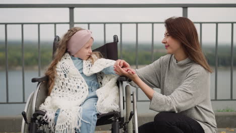 loving mom gently strokes hand of daughter with disability