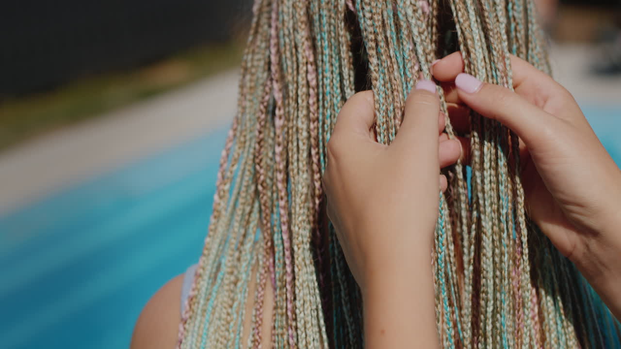 A woman admires her daughter's Afro-braids, holds them in her hand. Stand by the pool.4k video