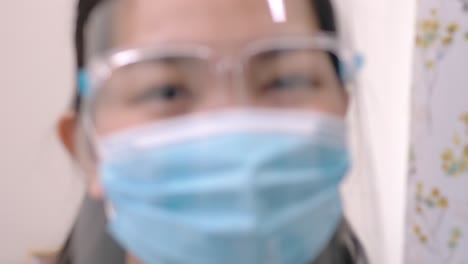 Portrait-of-an-Asia-young-female-who-is-wearing-a-face-shield-with-mask-rounded-around-her-face-from-a-frontal-perspective-to-protect-her-glasses-and-eyes,-scene-of-slow-motion