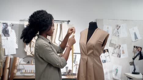 young woman, clothing designer making measurements with a measuring tape of the new dress in studio