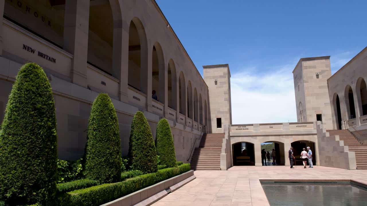 Una toma panorámica captura la arquitectura de arenisca, la lámina de agua y los setos topiarios cuidados en Canberra