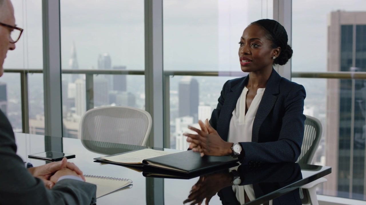Opening black folder, woman in navy blazer sliding papers, gesturing to secure job in office