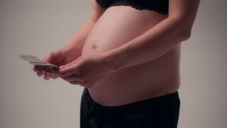 pregnant woman looks through ultrasound photos while waiting for baby
