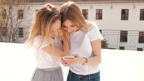 two happy young women looking at a phone on a rooftop