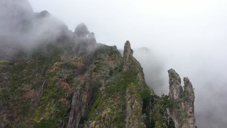 toma de drones del valle de las monjas en madeira, moviéndose lateralmente a lo largo de los picos afilados y puntiagudos entre las nubes delgadas y espeluznantes