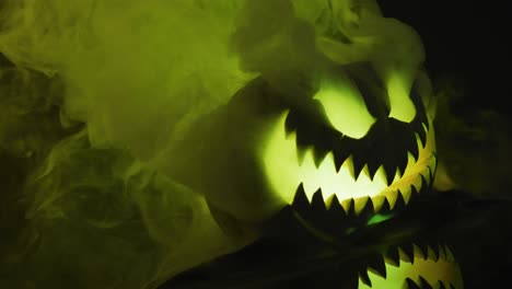 Video-of-halloween-carved-pumpkin-with-smoke-and-green-light-on-black-background