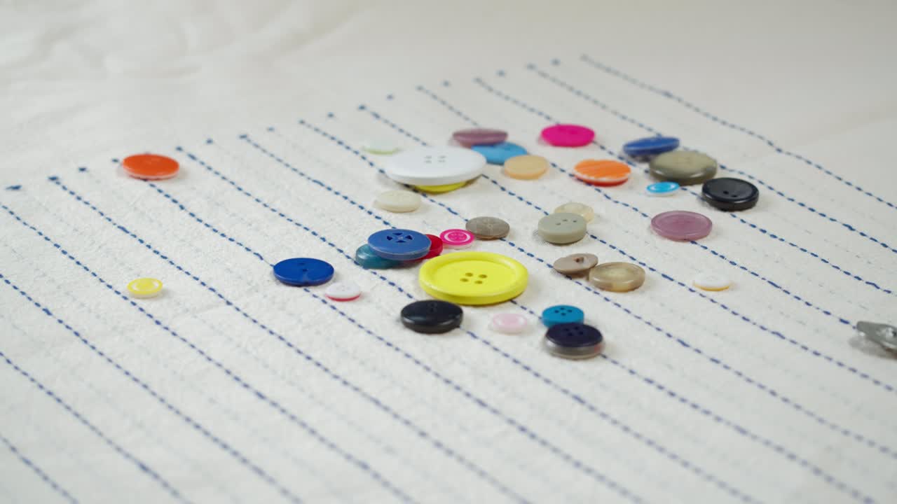 다채로운 버튼이 줄무 천에 떨어지는 클로즈업. 옷을 는 것과 전문적인 바느질 개념. 재료에 대한 버튼 액세서리를 선택하는 것.