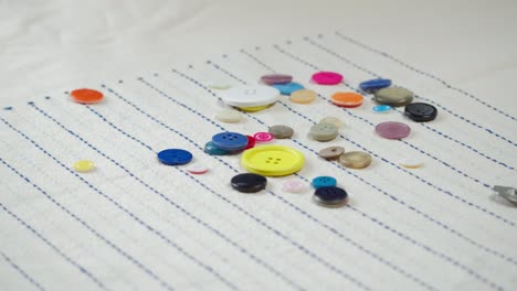 botones coloridos que caen en la tela a rayas de primer plano. confección de ropa y concepto de costura profesional. elección de accesorios de botones para el material
