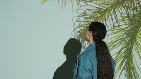 mujer visitando una exposición de arte inmersivo interactuando con imágenes de hojas de palma proyectadas en su cuerpo