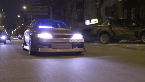 modified car driving at night on city street in winter