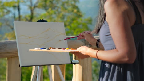 woman painting mountains outdoors