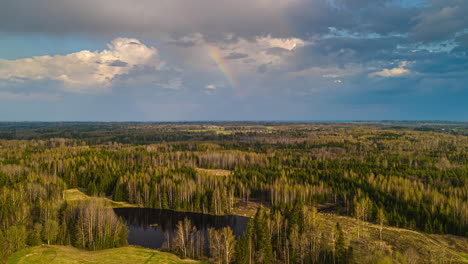 clouds drift by over a rural landscape with forests and a lake.