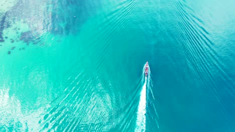 barco navegando lentamente en la tranquila superficie del mar turquesa que refleja la luz del sol cerca de la costa de la isla tropical con arrecifes de coral en los fondos marinos en camboya