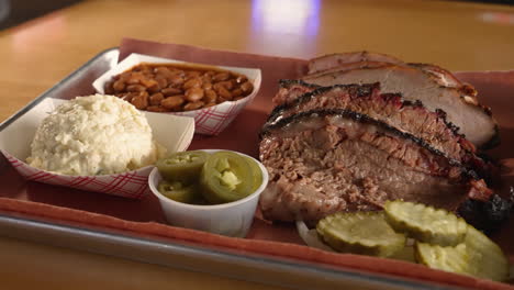 Moist-sliced-brisket-and-turkey-on-traditional-Texas-barbecue-two-meat-plate,-slider-close-up-4K