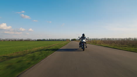 biker rides on a rural road tractor rides past him hd video