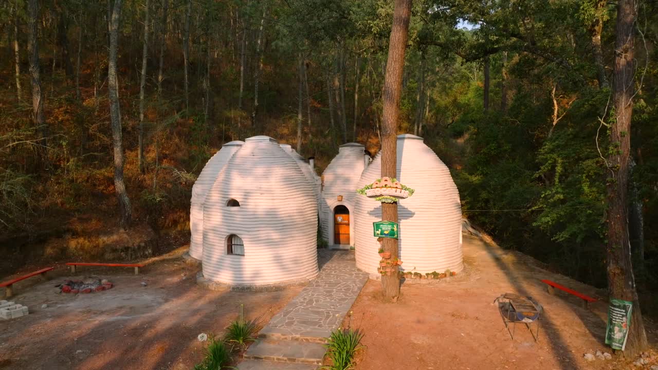 Round superadobe dome structures with small windows in wooded eco park setting in Tapalpa, Mexico