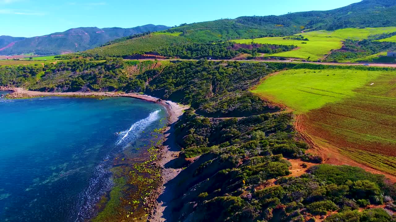 해가 지는 산과 바다 사이의 절벽 쪽에 있는 도로의 공중 드론  ⁇