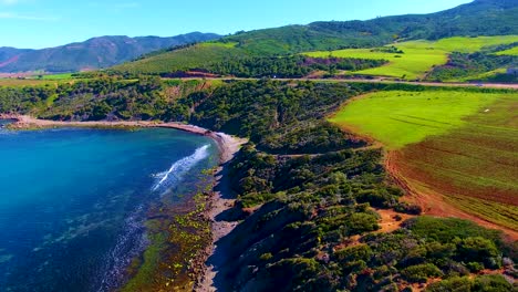 disparo aéreo de un avión no tripulado de una carretera en el lado del acantilado entre la montaña y el mar al atardecer