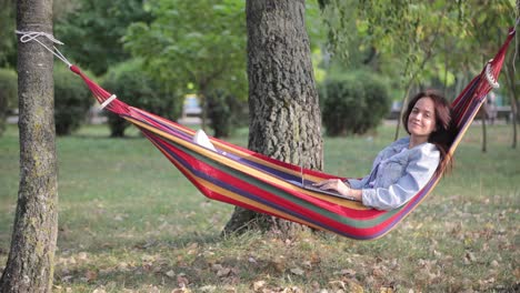 woman relaxing in a hammock with a laptop in a park