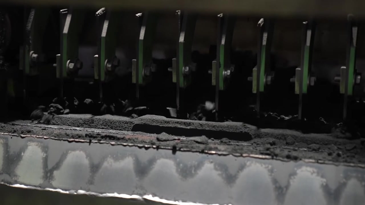 Sand filling and compacting machine depositing black molding sand into casting flask